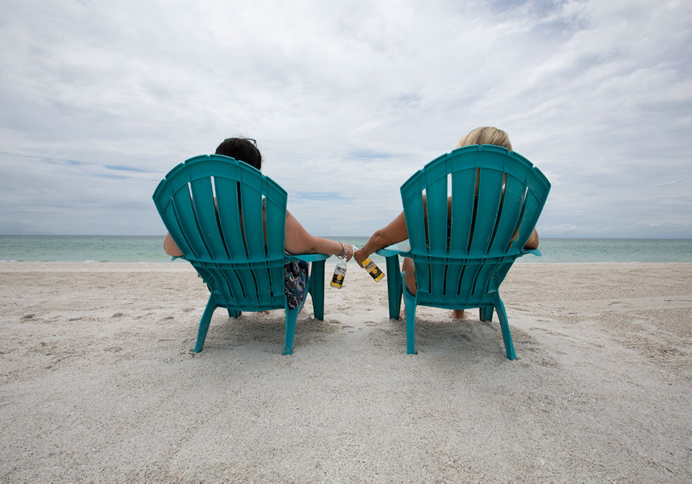 Before Photo: of two woman on lawn chairs sitting on the beach holding corona's while looking at the blue ocean