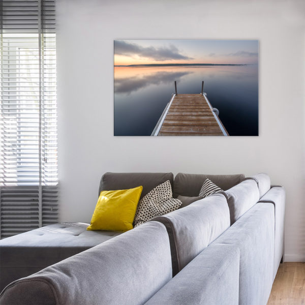 Photograph on canvas in the living room. Photograph is of a dock by the lake on a morning sunrise.