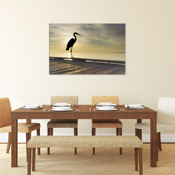 Photograph on canvas in the kitchen of a heron on a pier during the morning sunrise.