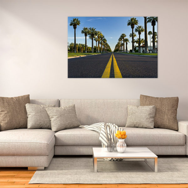 Photograph on canvas in the living room. Photograph is of a road surrounded by palm trees and blue skies.